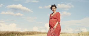Portrait d’une femme enceinte dans un champ de blé sous un ciel bleu