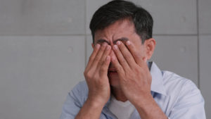 un homme qui se frotte les yeux