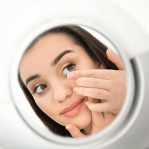 femme qui essaie de mettre des lentilles de contact